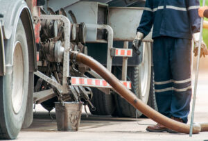 worker beside an oil hose attached to a truck