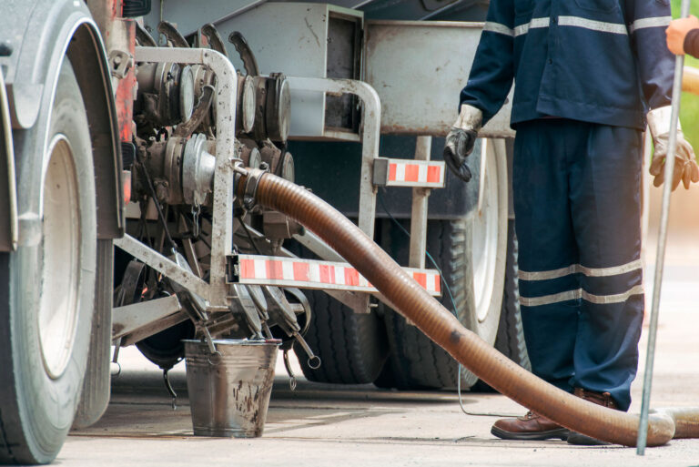 worker beside an oil hose attached to a truck